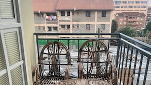 Un balcón con dos sillones de mimbre y vista a edificios al fondo.