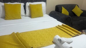 Una habitación de hotel con una cama grande, dos almohadas, un sofá gris y decoración en la pared.