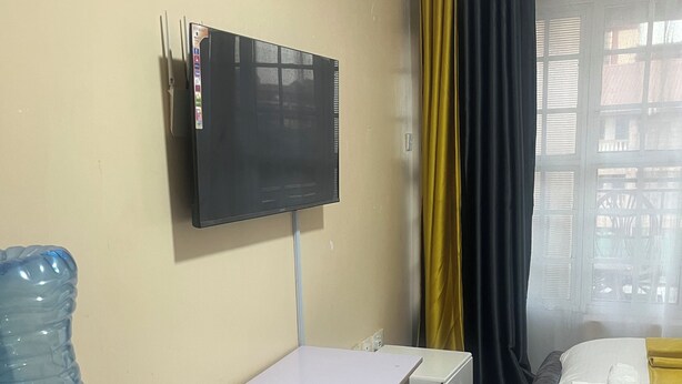 Une chambre d’hôtel équipée d’un lit, d’un bureau, d’une télévision, d’un distributeur d’eau et d’une fenêtre avec des rideaux.