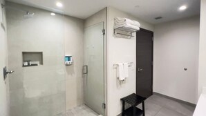 A modern bathroom with a glass-enclosed shower, a dark door, and a small bench. - Rent Apart Hollywood (Hollywood)