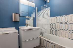 Ein Badezimmer mit weißem Waschbecken, Spiegel und einer Duschkabine aus Glas.