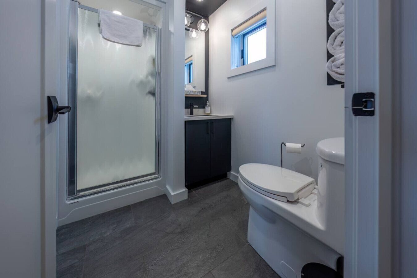 Un baño moderno con ducha vidriada, inodoro y lavabo.