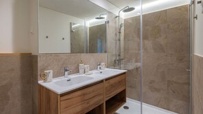 Ein modernes Badezimmer mit zwei Waschbecken, einer Duschkabine aus Glas und einem großen Spiegel.