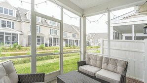 A covered patio with a cushioned seating area, large windows, and string lights. - Tastefully FULL furnished, 3 bedrooms with 3.5 bath townhouse. (Rehoboth Beach)