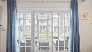 A room with a sliding glass door leading to an outdoor patio area with wicker furniture and a view of houses. - Tastefully FULL furnished, 3 bedrooms with 3.5 bath townhouse. (Rehoboth Beach)