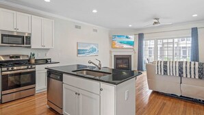 A modern kitchen with stainless steel appliances, a central island with a sink, and a fireplace. - Tastefully FULL furnished, 3 bedrooms with 3.5 bath townhouse. (Rehoboth Beach)