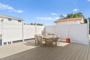 Eine Holzterrasse mit Tisch und Stühlen, umgeben von einem weißen Zaun.