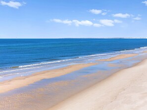 Uma praia com águas azul-claras e uma extensa faixa de areia.