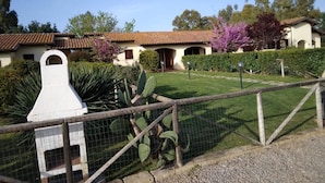 A fenced property with a white structure, cacti, and a building with a tiled roof. - Agriturismo Canova - Private Villas (Grosseto)