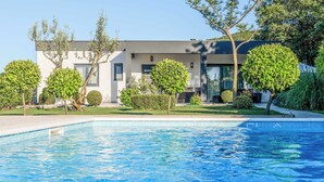 Una casa moderna amb piscina, envoltada de gespes cuidades i arbres.