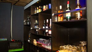 Zona de bar con estantes llenos de botellas y vasos.