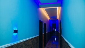 Un pasillo con paredes azules y suelo de mármol, que conduce a una puerta al final.