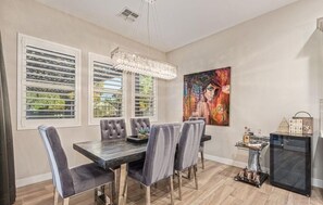 A dining area with a table, chairs, a chandelier, a painting, and a refrigerator. - Desert Sky Stay on 34th in Vibrant Phoenix (Phoenix)