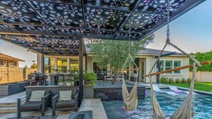 Um pátio externo com piscina, área de estar e pérgola.