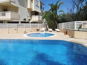 Ein Pool mit weißem Deck, einer Palme und einem Gebäude mit Balkonen.