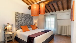 Une chambre à coucher comprenant un lit, deux tables de chevet, un climatiseur fixé au mur et une fenêtre avec des rideaux.