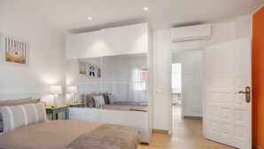 Ein Schlafzimmer mit einem Bett, Nachttischen, einem Kleiderschrank und einer Tür zu einem anderen Raum.