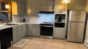 Una cocina con gabinetes grises, un refrigerador de acero inoxidable, un microondas y un lavavajillas.