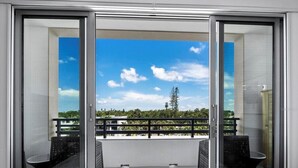 Varanda com vista desobstruída para o céu e árvores, com duas cadeiras de vime preto e uma mesa pequena.
