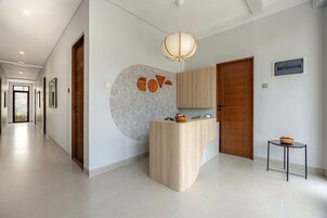 A modern reception area with a wooden reception desk, a hanging light fixture, and a small table with a bowl of fruit.