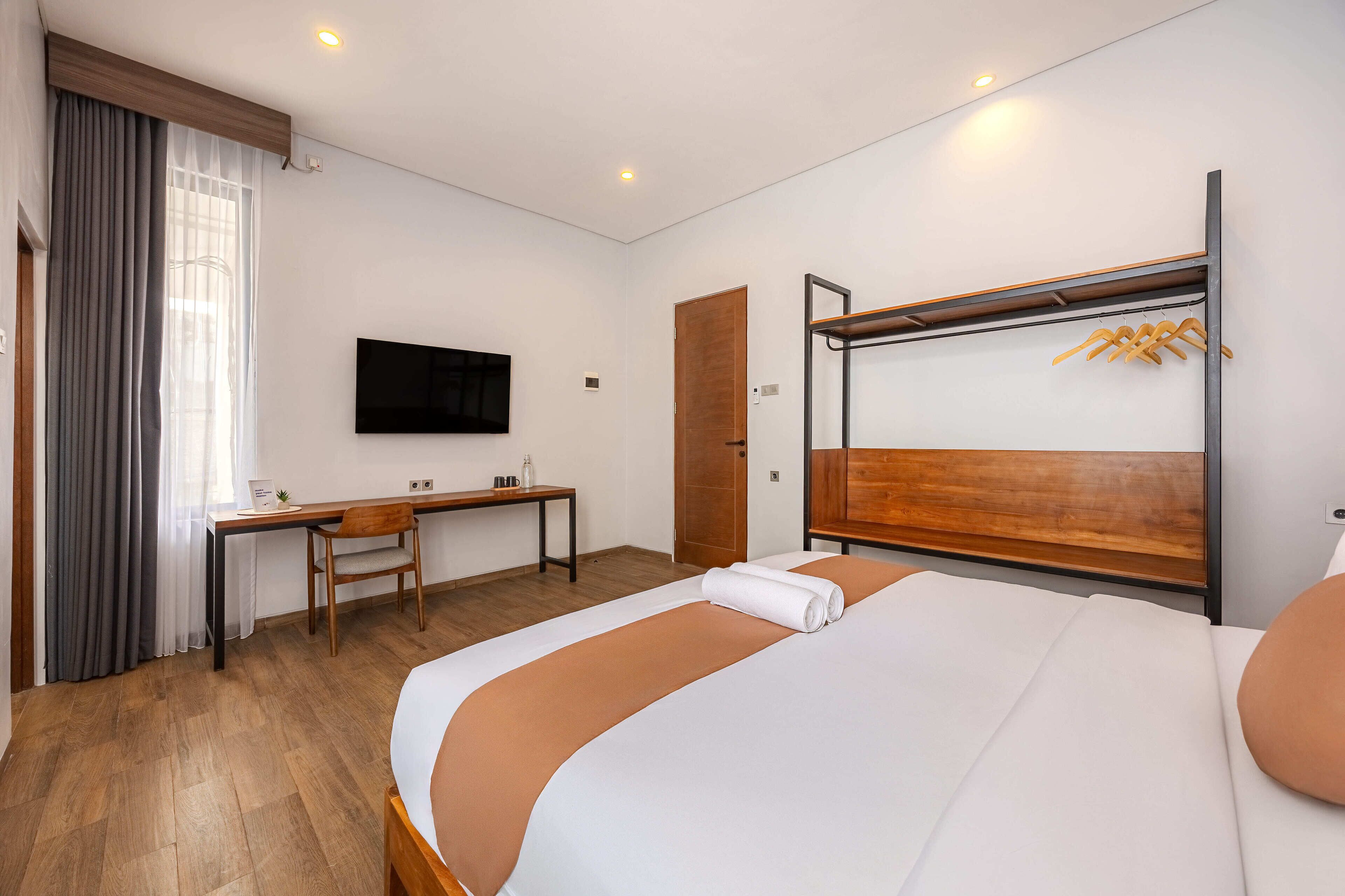 A hotel room with a bed, a desk, a chair, a TV, and a wardrobe.