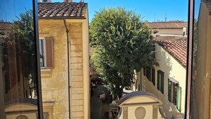 A narrow street with buildings featuring traditional architecture, including tiled roofs and a tree in the center. - StudioAttic | Historic Center | Renovated 2025  | Air Conditioning (Firenze)