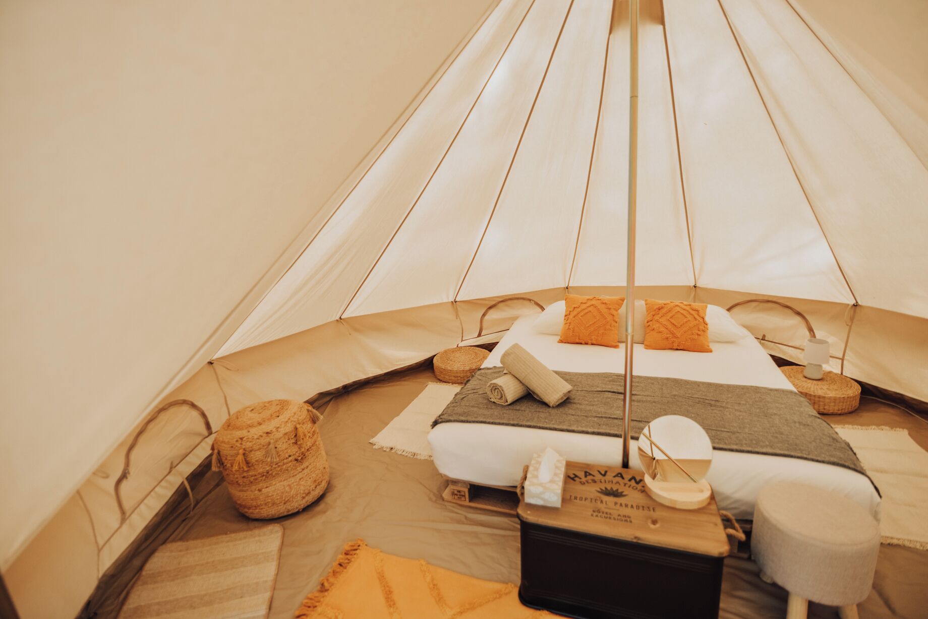 Ein Zelt mit Bett, Kissen, einem kleinen Tisch und einem Koffer.