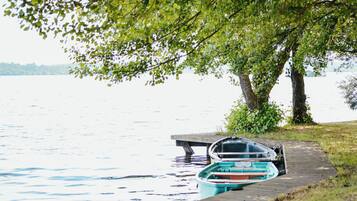 A dock with a rowboat and a small boat tied to it, overlooking a calm lake.