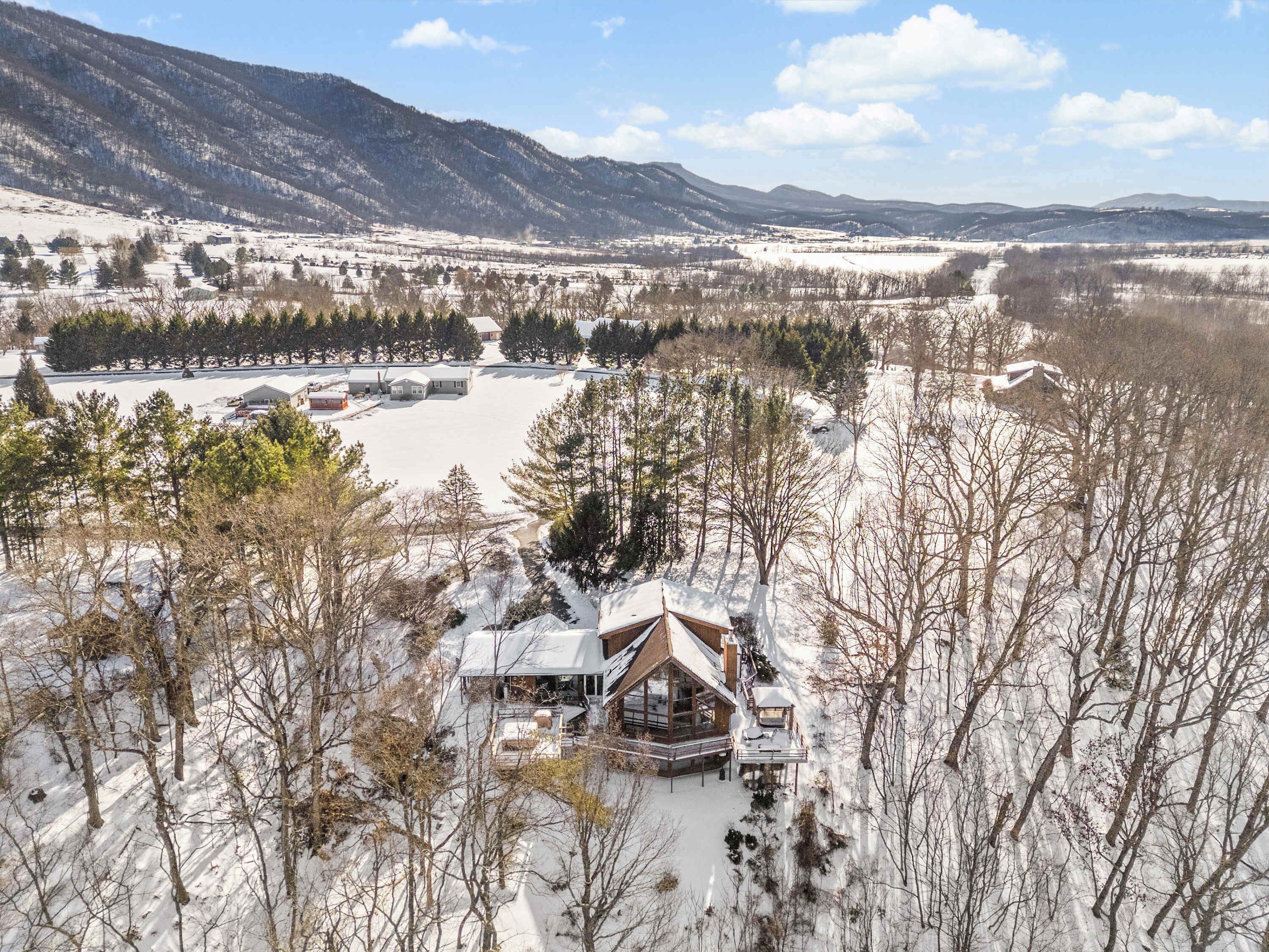 A lodge with a large deck and a view of a snowy landscape and mountains.