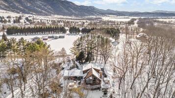 A lodge with a large deck and a view of a snowy landscape and mountains.