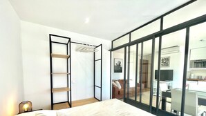 Un dormitorio con cama, armario, televisor y kitchenette.