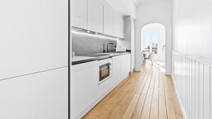 Eine moderne Küche mit weißen Schränken, einer schwarzen Arbeitsplatte und einem Holzboden.