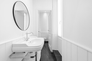 A modern bathroom with a white sink, a mirror, and a toilet. - riviera signature (Cannes)