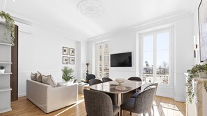 Ein modernes Wohnzimmer mit Esstisch, Sofas und einem Fernseher.