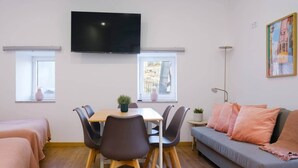 A modern living room with a dining table, sofa, and TV. - NEW! House w/HotTub by Douro River & Iconic Bridge (Vila Nova de Gaia)
