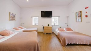 A hotel room with four single beds, a desk, two windows, a flat-screen TV, and a small table with a plant. - NEW! House w/HotTub by Douro River & Iconic Bridge (Vila Nova de Gaia)