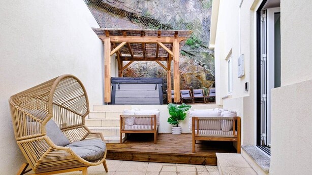 A cozy outdoor seating area with wicker furniture, a wooden pergola, and a view of a rocky landscape. - NEW! House w/HotTub by Douro River & Iconic Bridge (Vila Nova de Gaia)