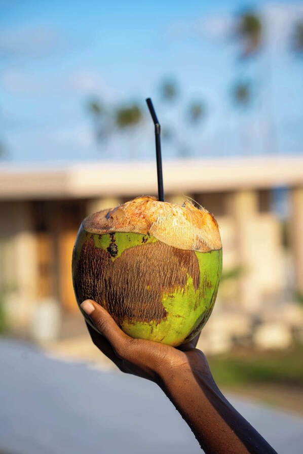 Une main tenant une noix de coco avec une paille.