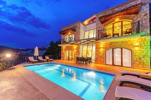 A modern house with a swimming pool, stone exterior, and outdoor seating area. - Villa Meltem Luxury Villa with Private Pool & Panoramic Sea Views – Kalkan (Antalya)