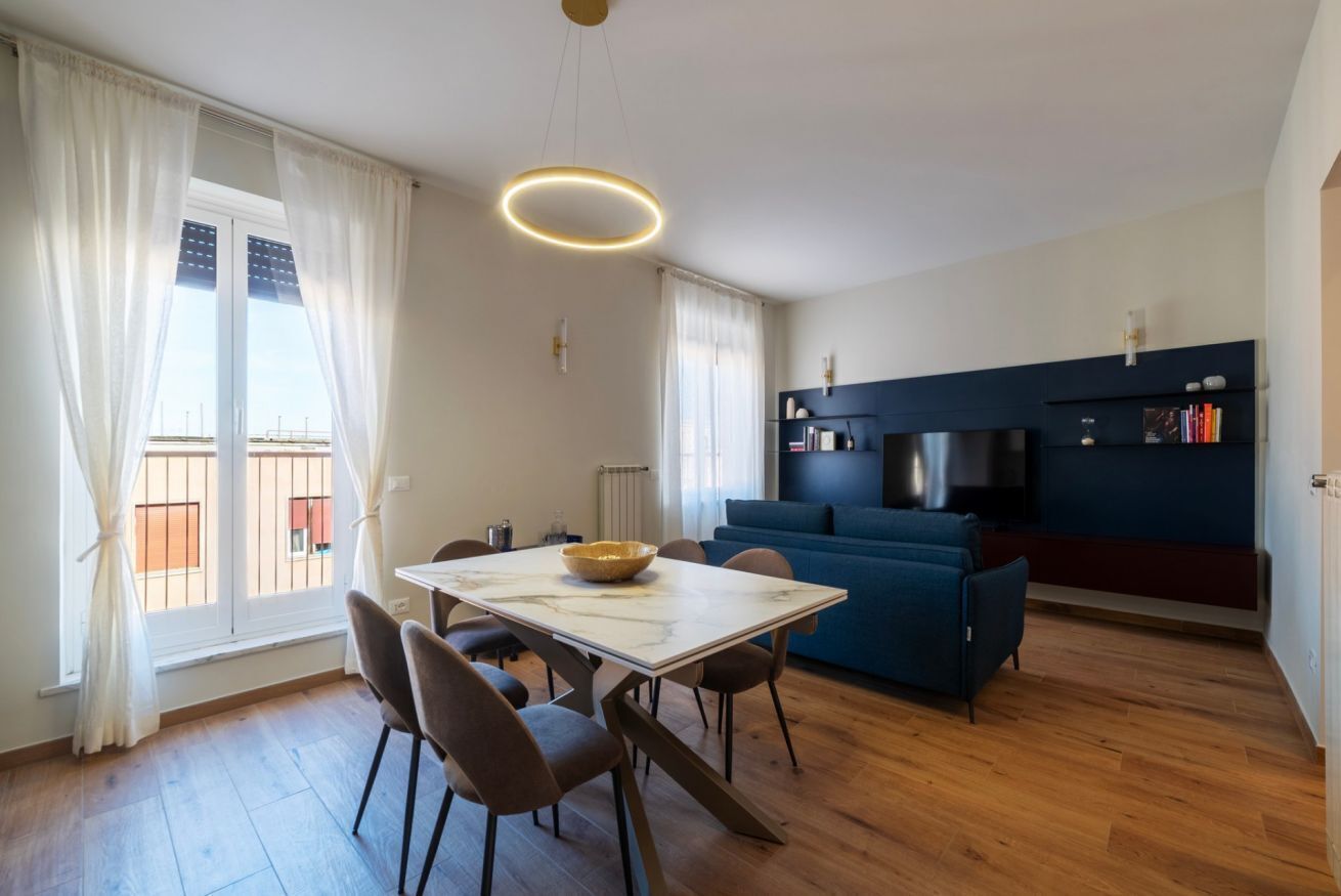 Et moderne køkken med spisebord, stole, en blå sofa og et fjernsyn.