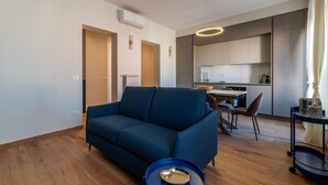 Een moderne woonkamer met een bank, een eettafel en een keukenhoek.