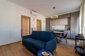 A modern living room with a sofa, a dining table, and a kitchen area. - GuestHost - A modern and welcoming 108 square meters apartment, perfect for five people, located on the sixth and top floor of a period building with an elevator (NOT accessible to guests with disabilities).The property is located in the elegant Prati di (Rome)