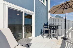 Een terras met een tafel en stoelen, een schuifdeur en een witte hek.