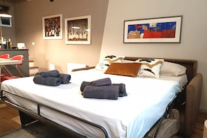 Una habitación de hotel con cama, escritorio y obras de arte en las paredes.