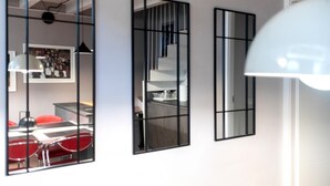 Tres espejos en la pared, un comedor con sillas rojas y una escalera.