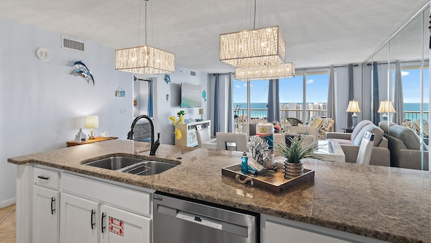 A modern kitchen with granite countertops, stainless steel appliances, and pendant lighting. - 🌴Walk to Beach | Gulf Views | Pelican Terrace 1404🌴 (Destin)