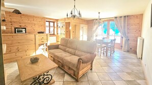A cozy living room with a sofa, a coffee table, and a dining area with a table and chairs. - House in the heart of the Jura (Saint-Laurent-en-Grandvaux)