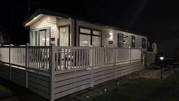 A mobile home with a fenced patio area, a covered outdoor seating space, and a visible garage door.