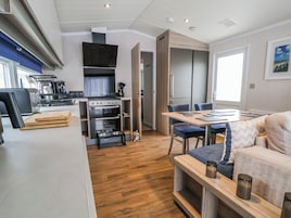 A compact kitchen with modern appliances, a dining area with a table and chairs, and a cozy seating area with cushions.