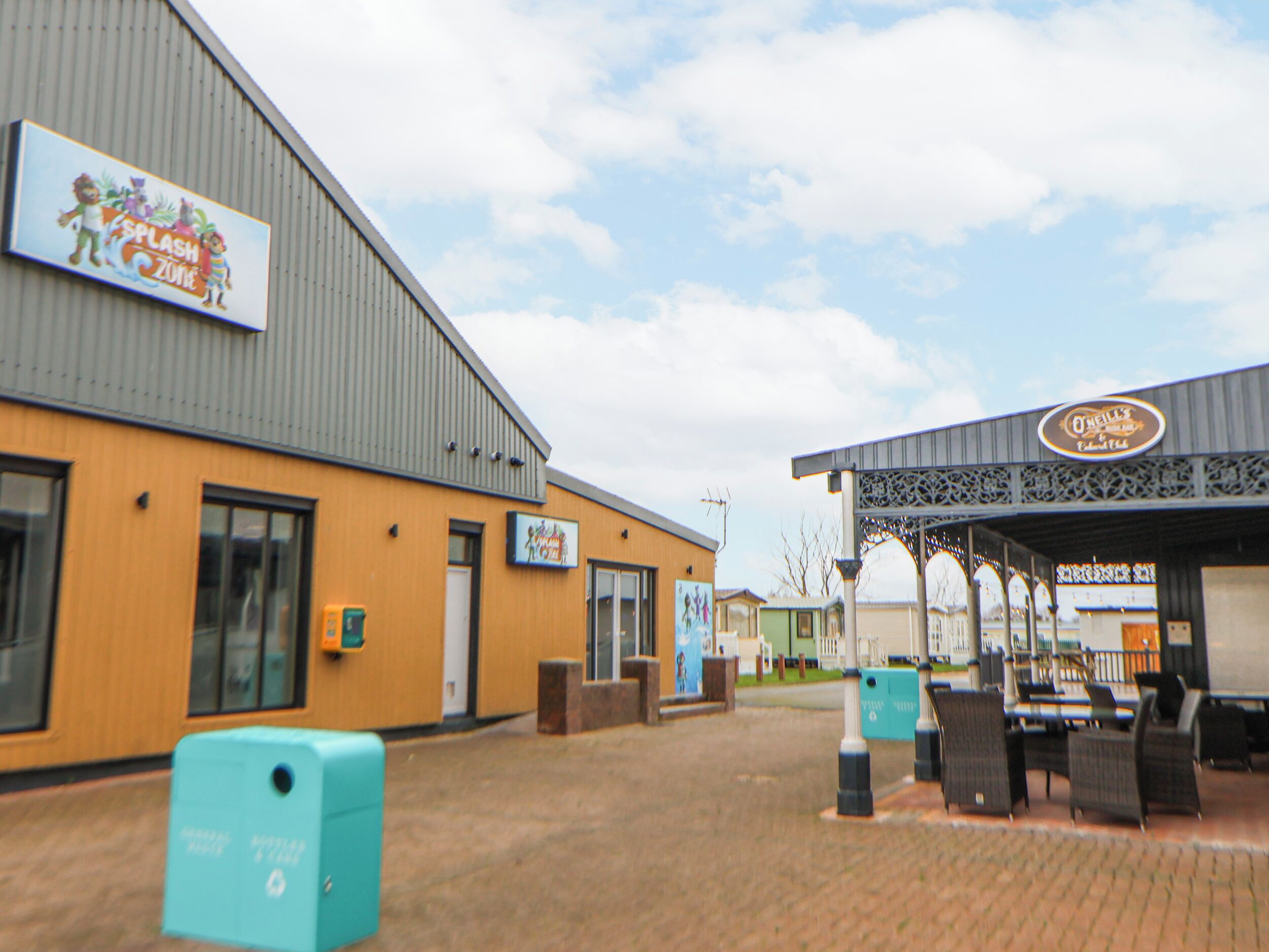 A building with a sign for Splash Zone, a covered outdoor seating area, and a sign for O'Neill's.
